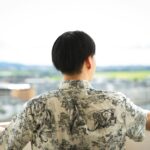unrecognizable man standing on open balcony against green city
